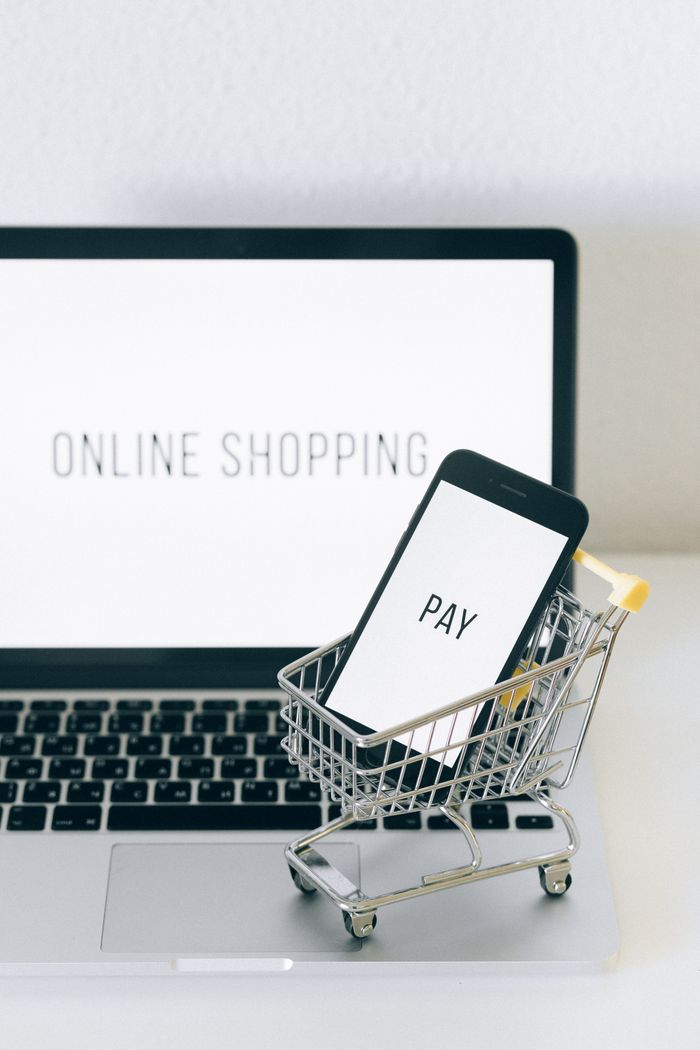 Home A smartphone in a miniature cart on a laptop symbolizes online shopping and digital payment.